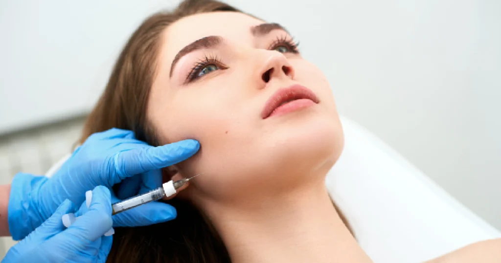 A woman receiving a Hyperdilute Radiesse facial injection in her cheek by a medical professional in Cleveland, OH.