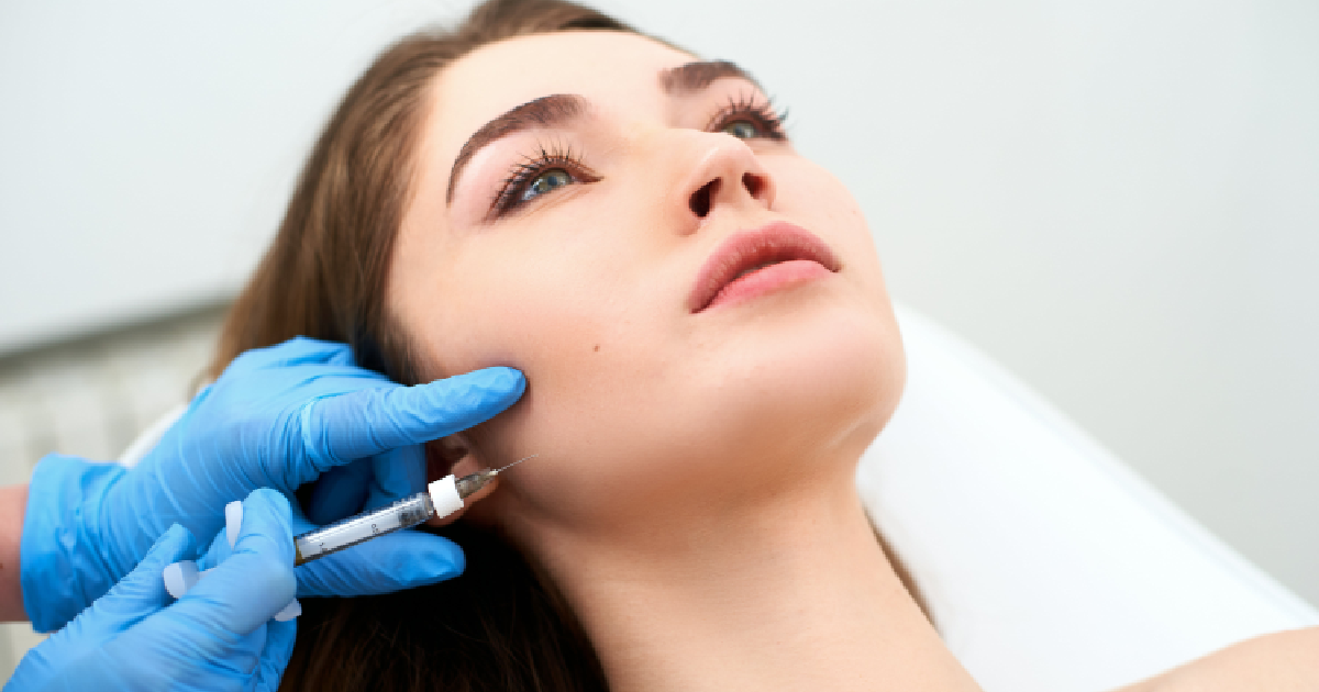 A woman receiving a Hyperdilute Radiesse facial injection in her cheek by a medical professional in Cleveland, OH.