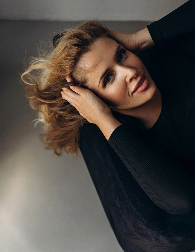 Blonde woman in black turtleneck posing with hand near face in artistic portrait photography - Redness and rosacea In Cleveland, OH