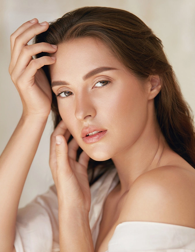 Natural beauty portrait of young woman with glowing skin and soft makeup touching face - Sculptra In Cleveland, OH