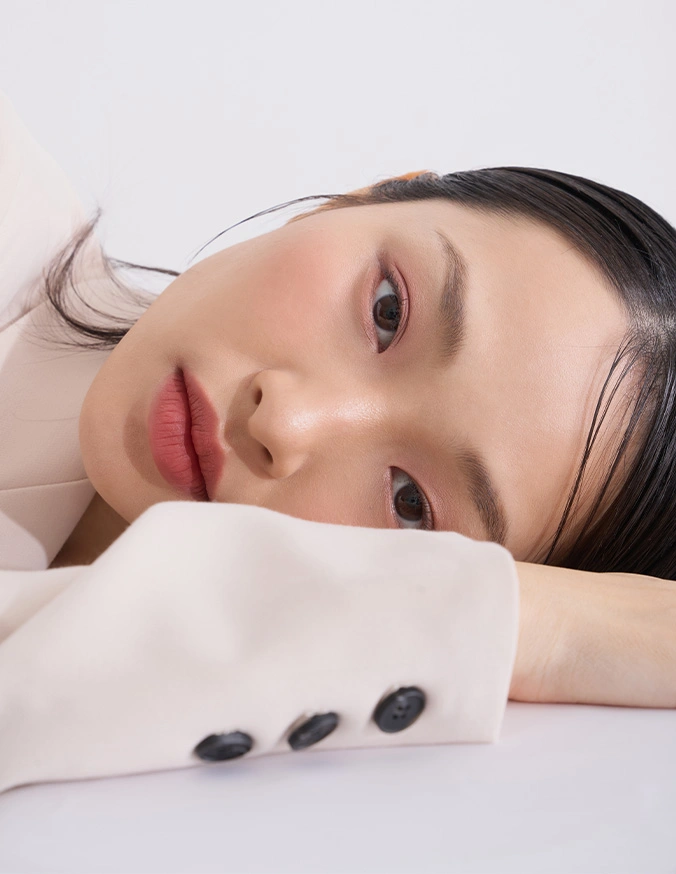 Young Asian woman with natural makeup resting on white surface with smooth stones for spa wellness treatment - Enlarged pores In Cleveland, OH